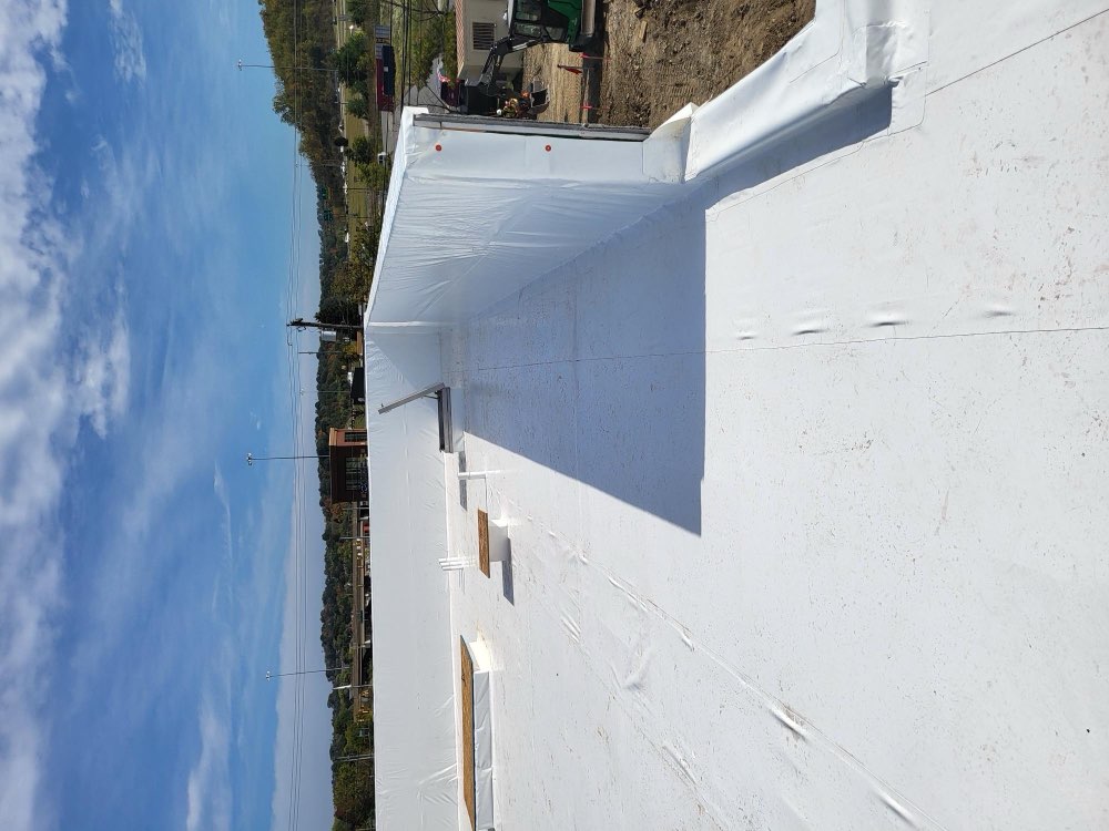 Commercial white TPO flat roof with a retail plaza behind it